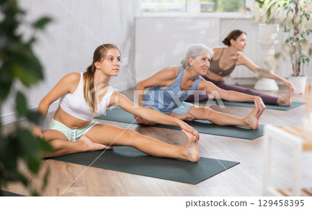 Teenage girl doing forward bending yoga pose Janu Sirsasana 129458395