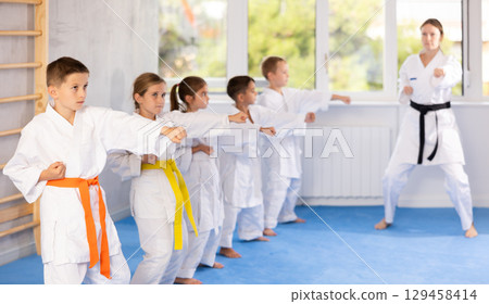 Children students repeat position and perform sequence of punches and painful techniques kata 129458414