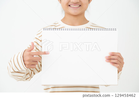 A middle school girl pointing at her sketchbook 129458462