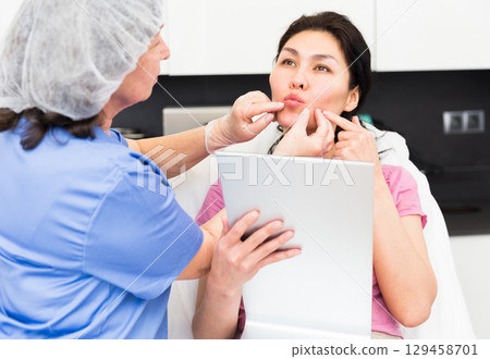 Cosmetologist consulting female patient in medical esthetic office 129458701
