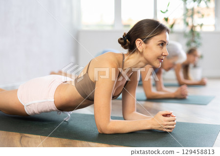 Three generations of women perform elbow plank Sampatasana in gym Three generations of women perform elbow plank Sampatasana in gym 129458813