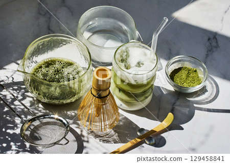 Matcha Preparation. Overhead view of matcha tools with frothy matcha drink Matcha Preparation. Overhead view of matcha tools with frothy matcha drink 129458841