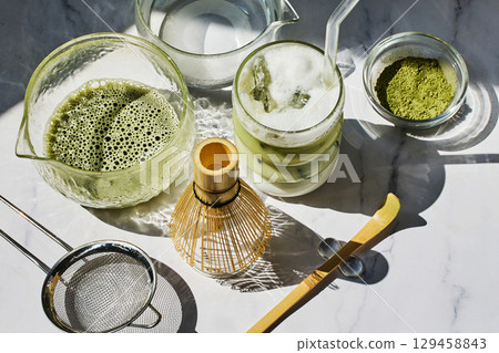 Matcha Preparation. Overhead view of matcha tools with frothy matcha drink Matcha Preparation. Overhead view of matcha tools with frothy matcha drink 129458843