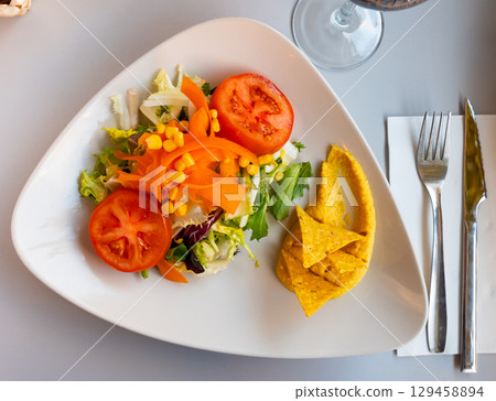 Salad with hummus and nachos served on plate Salad with hummus and nachos served on plate 129458894