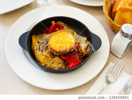 traditional spanish goat cheese with vegetables served in cast iron pan 129458901