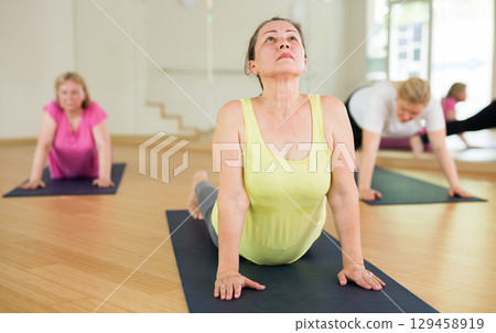Ladies are doing upward-facing dog pose 129458919