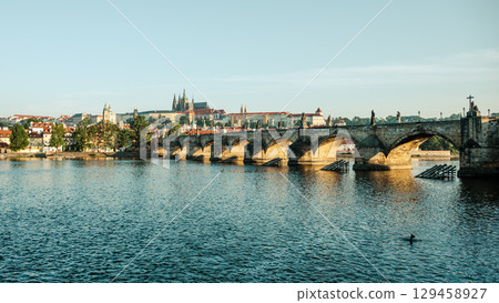 Morning light illuminates Prague Castle and Charles Bridge reflected in the Vltava River, showcasing the stunning architecture and peaceful atmosphere of Czechia's capital. Morning light illuminates Prague Castle and Charles Bridge reflected in the Vltava River, showcasing the stunning architecture and peaceful atmosphere of Czechia's capital. 129458927