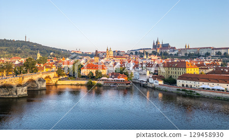 A breathtaking view of Prague at sunrise, showcasing the serene Vltava River and the iconic Charles Bridge. The morning light illuminates the medieval architecture, creating a magical atmosphere. A breathtaking view of Prague at sunrise, showcasing the serene Vltava River and the iconic Charles Bridge. The morning light illuminates the medieval architecture, creating a magical atmosphere. 129458930