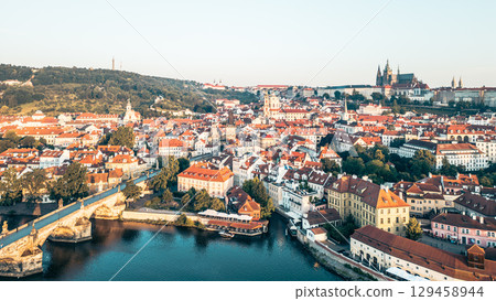 Aerial view capturing the beauty of Prague at sunrise, showcasing the Charles Bridge and Hradcany Castle bathed in morning light, with no people in sight. Aerial view capturing the beauty of Prague at sunrise, showcasing the Charles Bridge and Hradcany Castle bathed in morning light, with no people in sight. 129458944