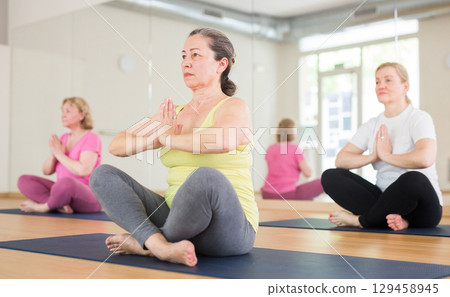 Ladies are sitting in a lotus pose 129458945
