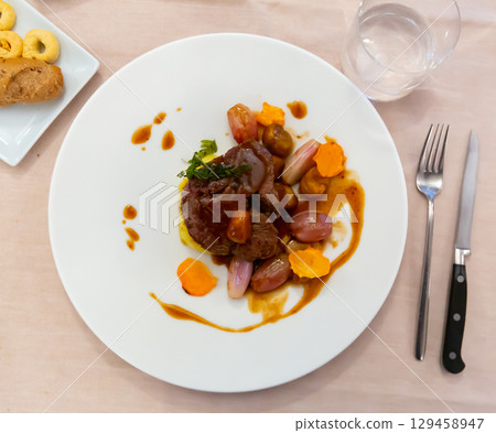 Veal loin marinated with rosemary served with chestnuts, shallots and potatoes Veal loin marinated with rosemary served with chestnuts, shallots and potatoes 129458947