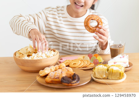 A middle school girl eating a lot of sweets 129458970