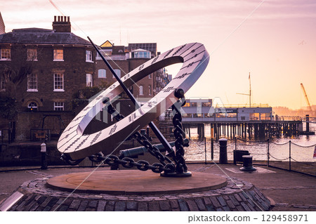 The Timepiece Sundial stands prominently along the Thames River in London, offering a unique way to tell time. Surrounded by historic buildings, it captures the essence of the city's charm at sunset. 129458971