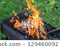 Fire brazier in a rustic metal pot amidst a grassy landscape 129460092