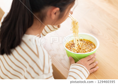 A middle school girl eating cup ramen in her room 129460395