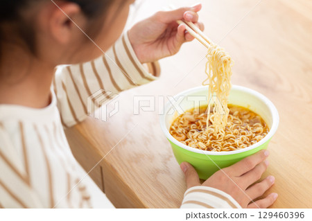 A middle school girl eating cup ramen in her room 129460396