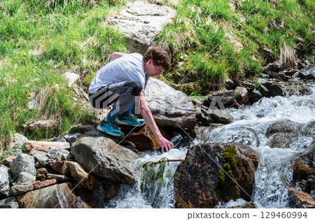 man collecting fresh mountain water from stream in the Austrian Alps man collecting fresh mountain water from stream in the Austrian Alps 129460994