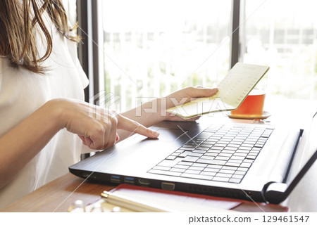 A woman managing her bank transaction history on a PC 129461547