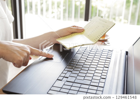 A woman managing her bank transaction history on a PC 129461548