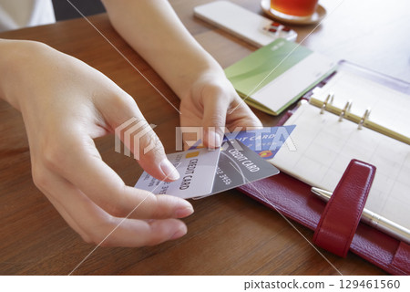 A woman managing her household finances while looking at multiple cards 129461560