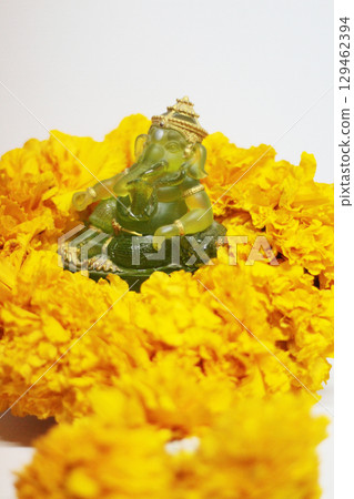 Emerald green Ganesha Statue god is the Lord of Success God of Hinduism on Marigold flowers Isolated on white background. Emerald green Ganesha Statue god is the Lord of Success God of Hinduism on Marigold flowers Isolated on white background. 129462394