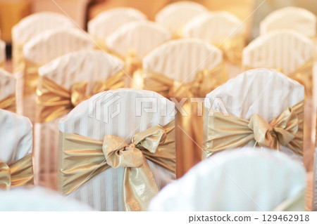 Beautiful chairs decoration with ribbon in wedding event hall, selective focus. Beautiful chairs decoration with ribbon in wedding event hall, selective focus. 129462918