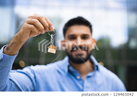 A man holding a house key, symbolizing homeownership and real estate. A man holding a house key, symbolizing homeownership and real estate. 129463042