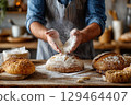 Rustic Kitchen Scene Baker Dusting White Flour On A Warm Loaf Of Bread, Wooden Table 129464407