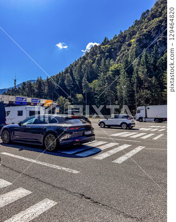 Vehicles waiting in line at a toll booth on a scenic mountain road under a clear blue sky.. High quality photo Vehicles waiting in line at a toll booth on a scenic mountain road under a clear blue sky.. High quality photo 129464820