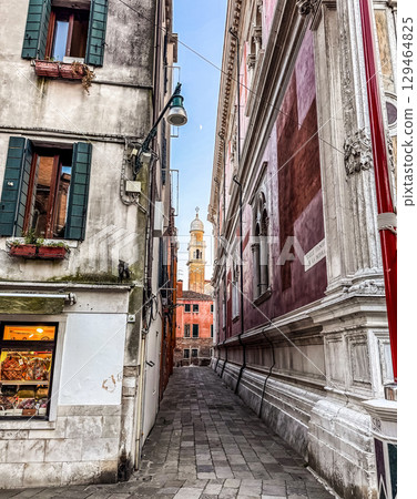Picturesque narrow alley in Venice with historic buildings and a distant bell tower.. High quality photo 129464825