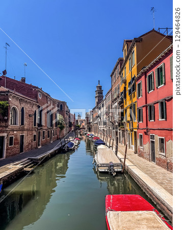Bright summer day in Venice, showing a calm canal lined with vibrant historic buildings and small boats. High quality photo Bright summer day in Venice, showing a calm canal lined with vibrant historic buildings and small boats. High quality photo 129464826