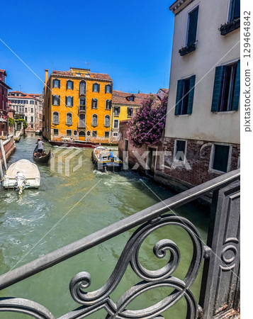 Boats passing along a narrow canal between colorful historic buildings in Venice, Italy.. High quality photo Boats passing along a narrow canal between colorful historic buildings in Venice, Italy.. High quality photo 129464842