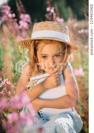 Young girl with a straw hat embraces a notebook in a flower field during sunset Young girl with a straw hat embraces a notebook in a flower field during sunset 129465068