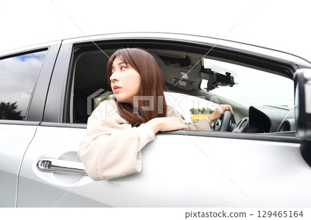 一位年輕的亞洲女性帶著微笑開車的車內景象 129465164