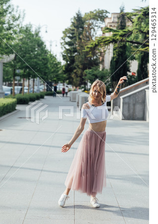 woman in dress dancing to music outdoors 129465314