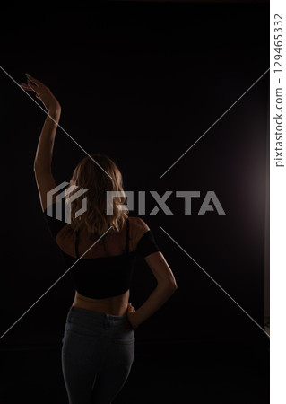 woman in jeans dancing to music on black background woman in jeans dancing to music on black background 129465332