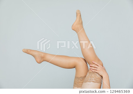 female legs in beige tights stockings on a white background 129465369