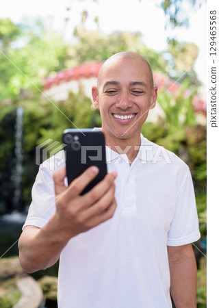 Modern man in Zen garden using smartphone, blending nature and technology Modern man in Zen garden using smartphone, blending nature and technology 129465568