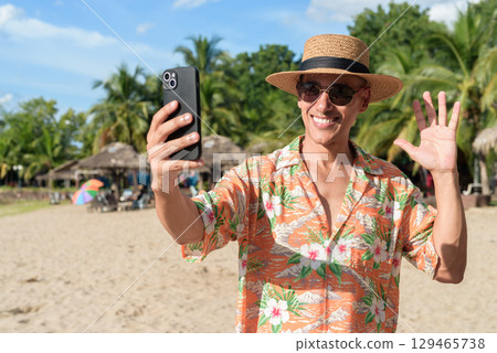 Hispanic Male Tourist in Panama Hat and Tropical Shirt Summer Vacation at Beach Using Phone Hispanic Male Tourist in Panama Hat and Tropical Shirt Summer Vacation at Beach Using Phone 129465738