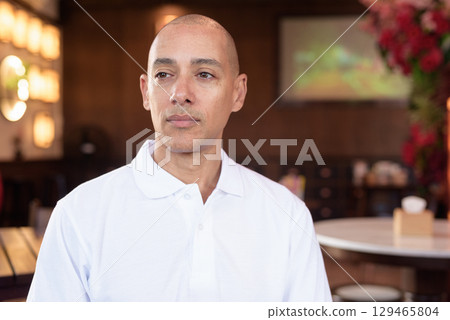 Confident Bald Hispanic face man in white polo shirt sitting in Chinese style coffee shop 129465804