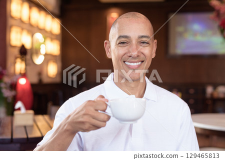 Bald Hispanic man in white polo shirt sitting in Chinese style coffee shop drinking coffee Bald Hispanic man in white polo shirt sitting in Chinese style coffee shop drinking coffee 129465813
