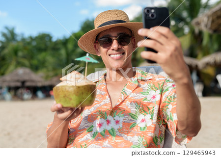 Hispanic man tourist sitting and using phone while having coconut water drink Hispanic man tourist sitting and using phone while having coconut water drink 129465943