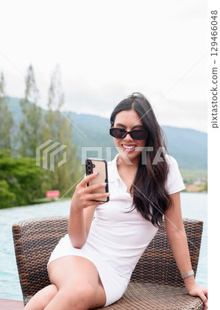 Asian woman in white polo shirt near swimming pool, outdoor nature, summer holiday portrait 129466048