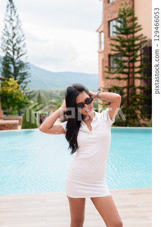 Asian woman in white polo shirt near swimming pool, outdoor nature, summer holiday portrait Asian woman in white polo shirt near swimming pool, outdoor nature, summer holiday portrait 129466053