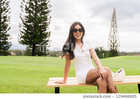 Asian woman in white polo shirt sitting at golf course, on greenery field, tourist lifestyle Asian woman in white polo shirt sitting at golf course, on greenery field, tourist lifestyle 129466085