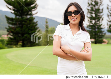 Asian woman in white polo shirt at golf course, on greenery field, tourist outdoor lifestyle 129466091