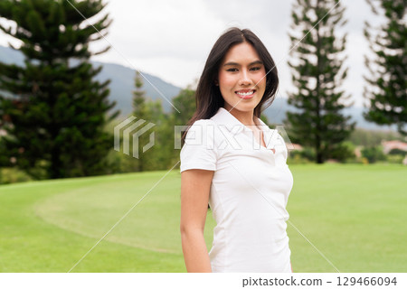 Asian woman in white polo shirt at golf course, on greenery field, tourist outdoor lifestyle 129466094