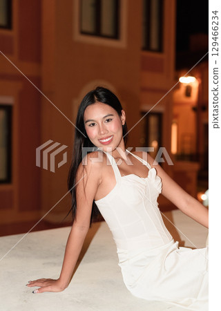 Young Asian woman tourist with long black hair in European style town at night Young Asian woman tourist with long black hair in European style town at night 129466234