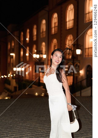Young Asian woman tourist with long black hair in European style town at night 129466248