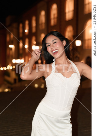 Young Asian woman tourist with long black hair in European style town at night Young Asian woman tourist with long black hair in European style town at night 129466252